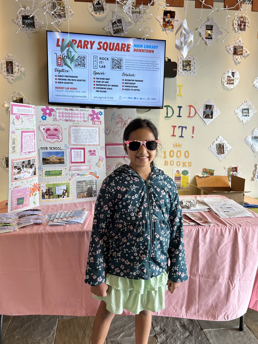A young visitor showing off decorated sunglasses by the display board